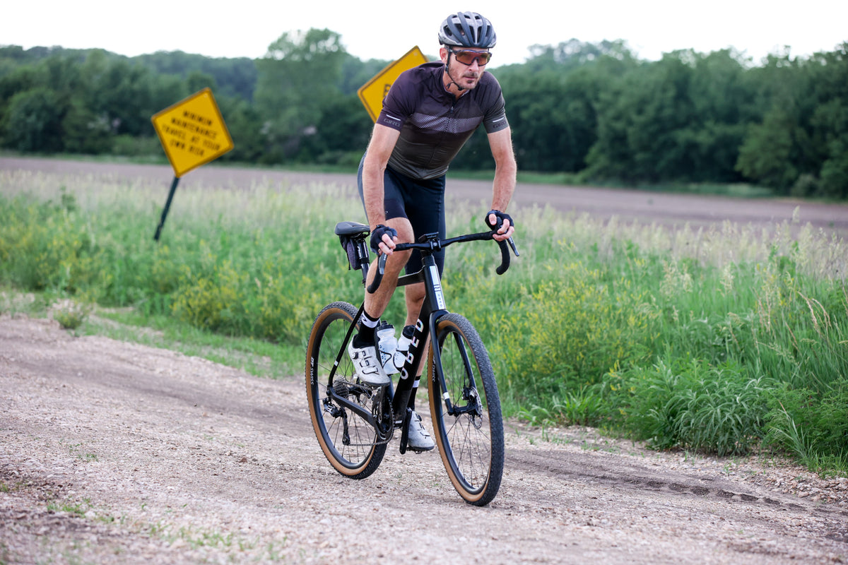 Cyclist riding on a gravel road with greenery in the background