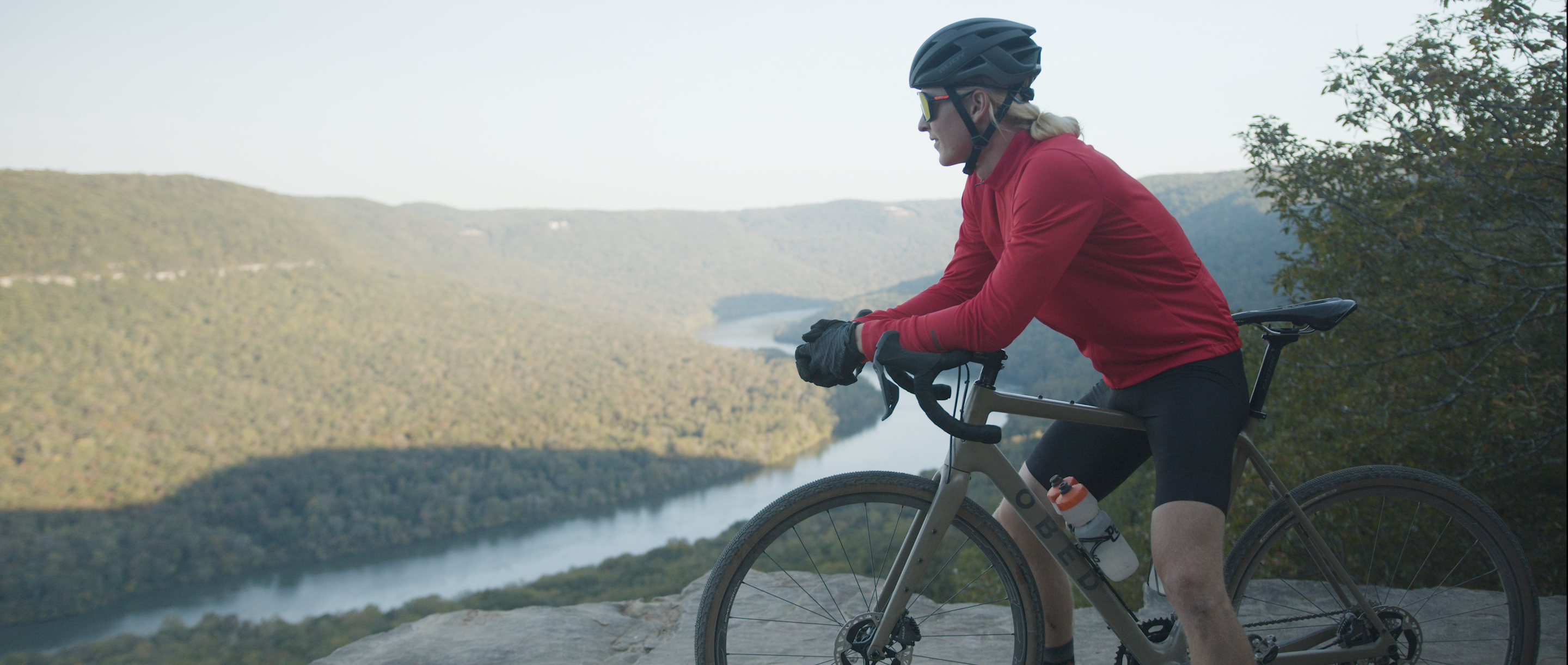 Man leaning on Boundary bike with river and mountain in the background